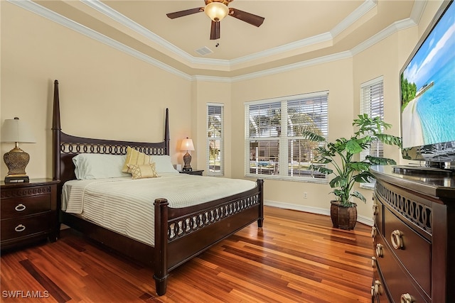 bedroom featuring ceiling fan, wood-type flooring, ornamental molding, and a tray ceiling