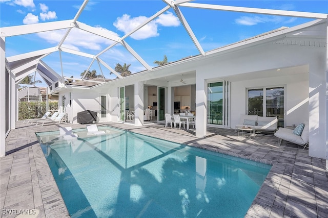 exterior space featuring glass enclosure, ceiling fan, a patio, and an outdoor living space