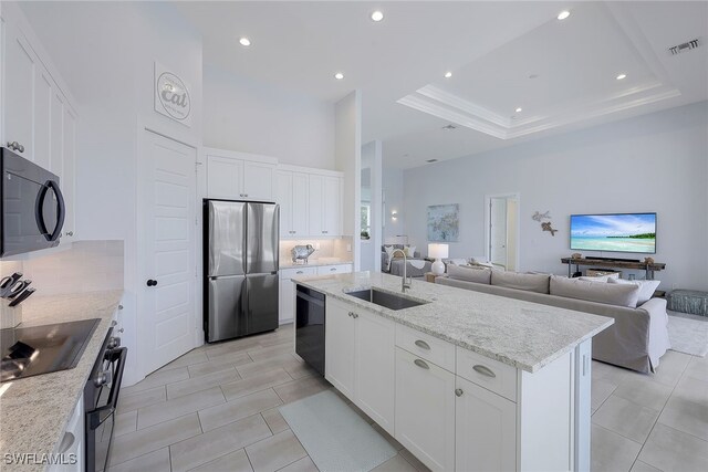 kitchen featuring light stone countertops, a kitchen island with sink, sink, black appliances, and white cabinets