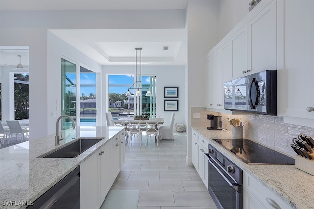 kitchen with sink, decorative light fixtures, white cabinetry, and black appliances