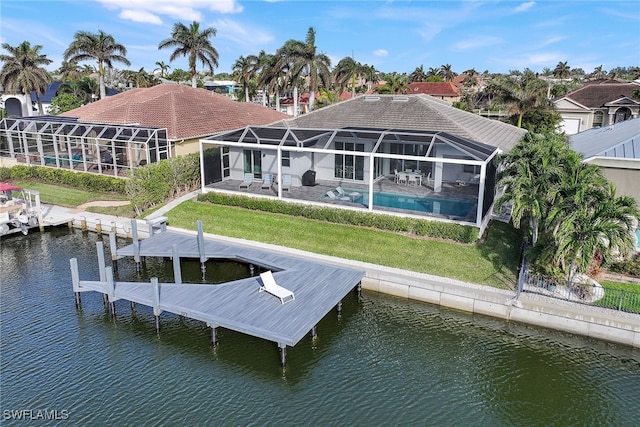 back of house with a lawn, glass enclosure, a water view, and a patio