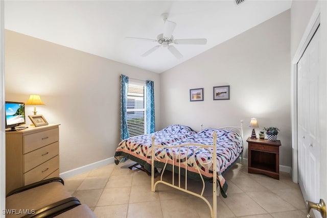 bedroom featuring ceiling fan, light tile patterned flooring, lofted ceiling, and a closet