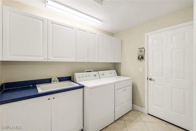 laundry room featuring cabinets, light tile patterned floors, washing machine and clothes dryer, and sink