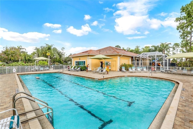 view of pool with glass enclosure and a patio area