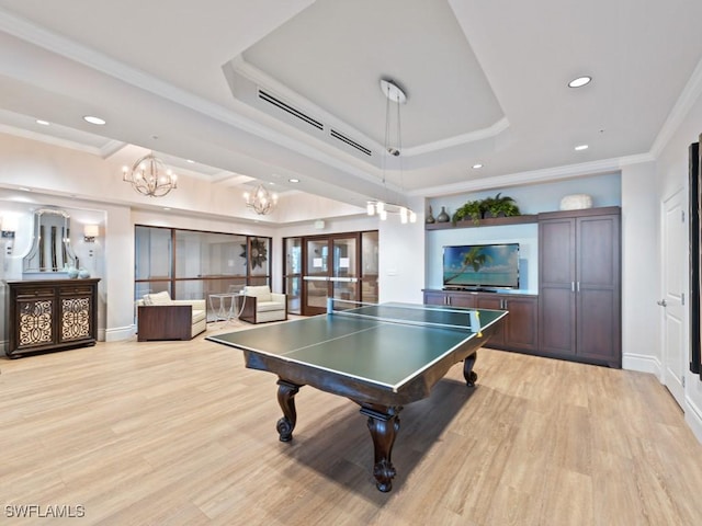 playroom featuring a tray ceiling, an inviting chandelier, ornamental molding, and light wood-type flooring