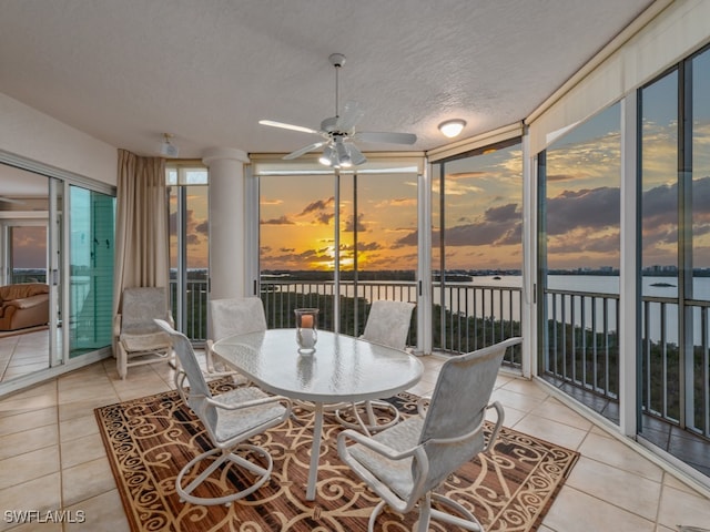 sunroom / solarium with ceiling fan and a water view