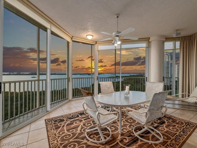 sunroom featuring plenty of natural light, ceiling fan, and a water view