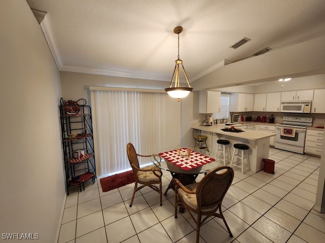 tiled dining room with crown molding, lofted ceiling, and sink