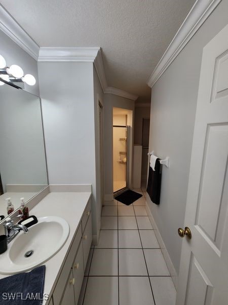 bathroom with crown molding, a textured ceiling, tile patterned flooring, and vanity