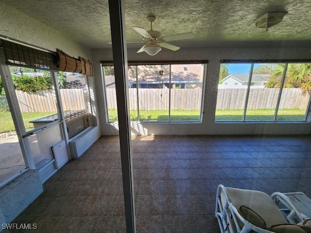 unfurnished sunroom with ceiling fan