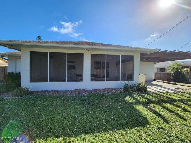 back of property with a sunroom and a lawn