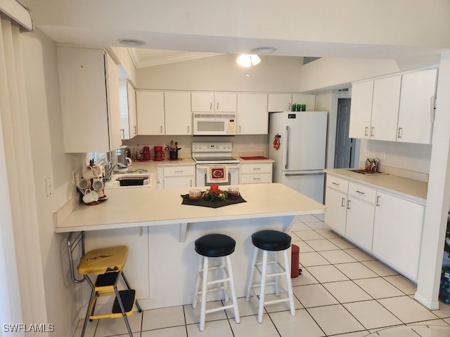 kitchen featuring light tile patterned flooring, a breakfast bar, sink, white cabinetry, and white appliances