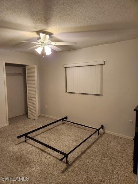 unfurnished bedroom with a closet, ceiling fan, carpet, and a textured ceiling