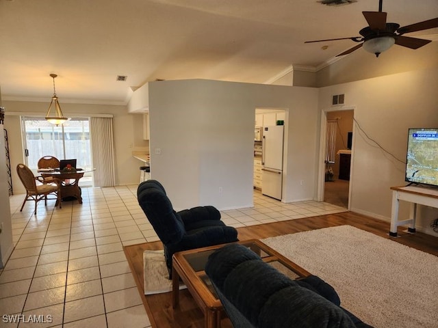 tiled living room with ceiling fan, ornamental molding, and vaulted ceiling