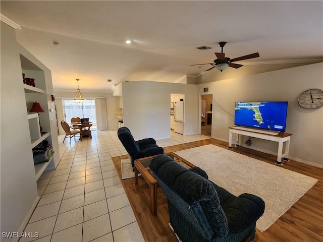 living room featuring ceiling fan, lofted ceiling, ornamental molding, and light hardwood / wood-style floors