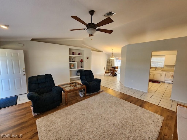 living area featuring vaulted ceiling, sink, light tile patterned floors, ceiling fan, and built in shelves