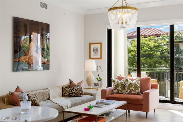 living room with ornamental molding, light hardwood / wood-style floors, and a notable chandelier