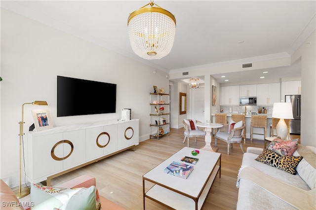 living room featuring a notable chandelier, light wood-type flooring, and ornamental molding