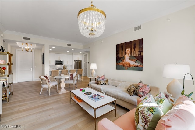 living room featuring light wood-type flooring, ornamental molding, and an inviting chandelier