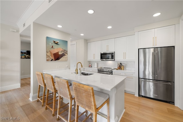 kitchen with sink, white cabinetry, light hardwood / wood-style floors, kitchen peninsula, and stainless steel appliances