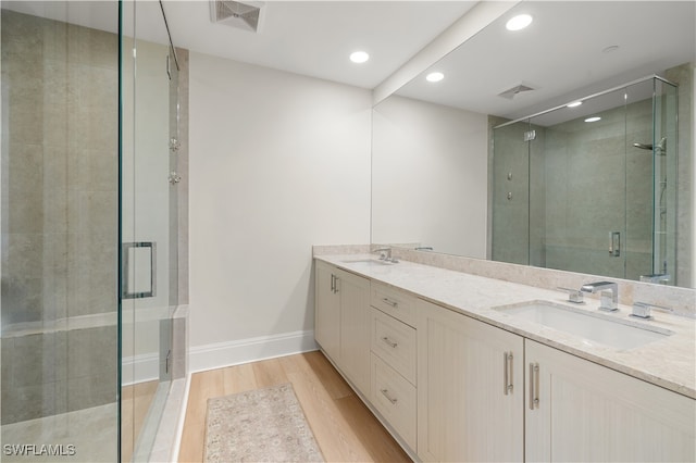 bathroom featuring hardwood / wood-style flooring, vanity, and a shower with door