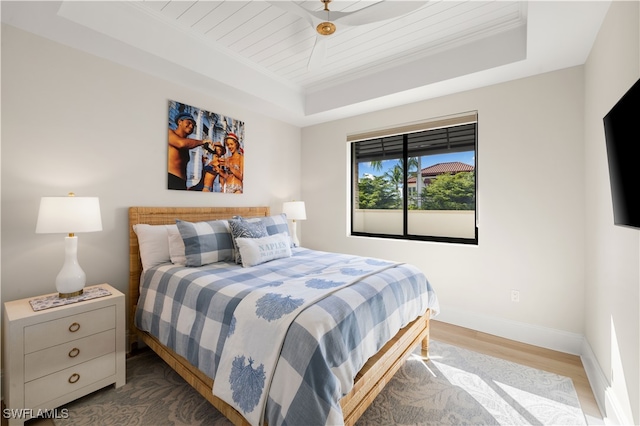 bedroom featuring hardwood / wood-style flooring, a raised ceiling, and crown molding