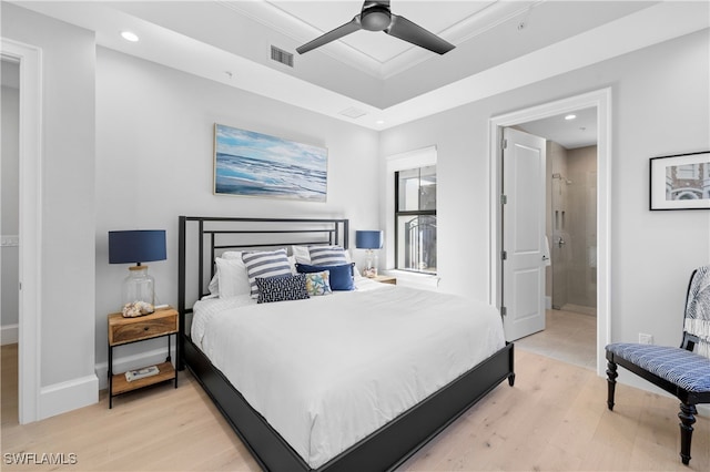 bedroom with light wood-type flooring, ensuite bathroom, and ceiling fan