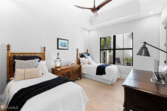 bedroom with a tray ceiling, light hardwood / wood-style flooring, and ceiling fan