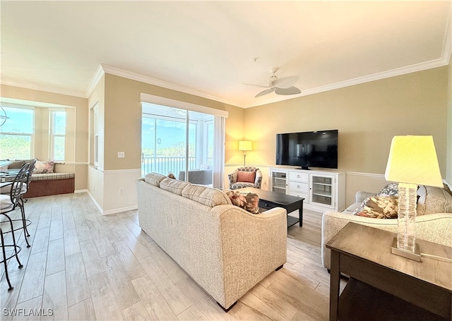 living room featuring ceiling fan, light wood-type flooring, ornamental molding, and a wealth of natural light