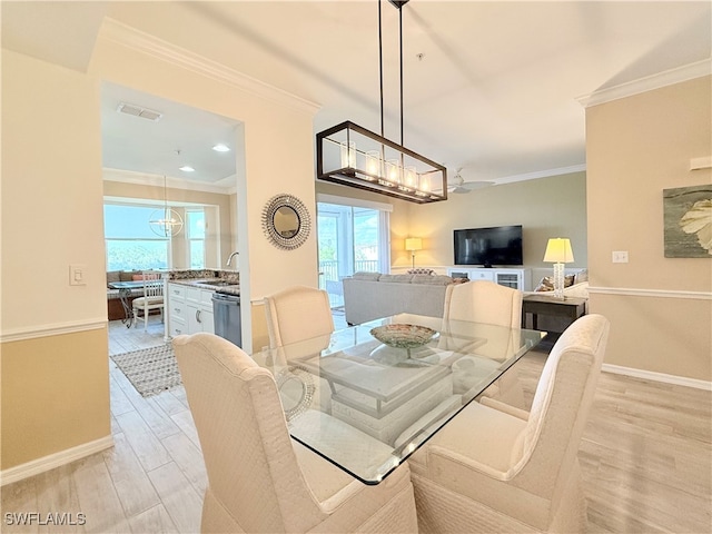 dining space with sink, light hardwood / wood-style flooring, and ornamental molding