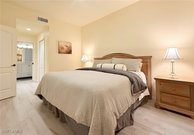 bedroom featuring light hardwood / wood-style flooring, ensuite bath, and ceiling fan