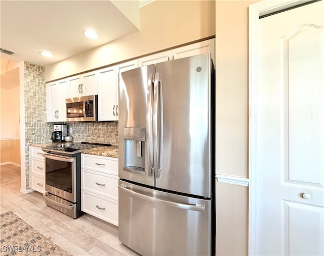 kitchen with decorative backsplash, white cabinetry, appliances with stainless steel finishes, and dark stone counters