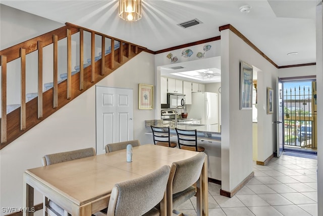 tiled dining area featuring ceiling fan and crown molding