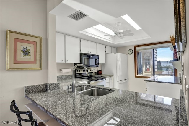 kitchen with white refrigerator, stone countertops, white cabinetry, and ceiling fan