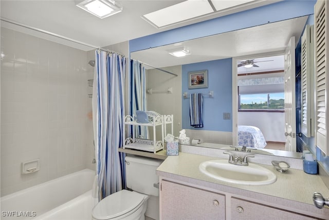 full bathroom featuring vanity, a skylight, ceiling fan, toilet, and shower / tub combo