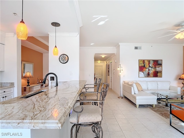 kitchen with pendant lighting, sink, crown molding, light tile patterned floors, and white cabinetry