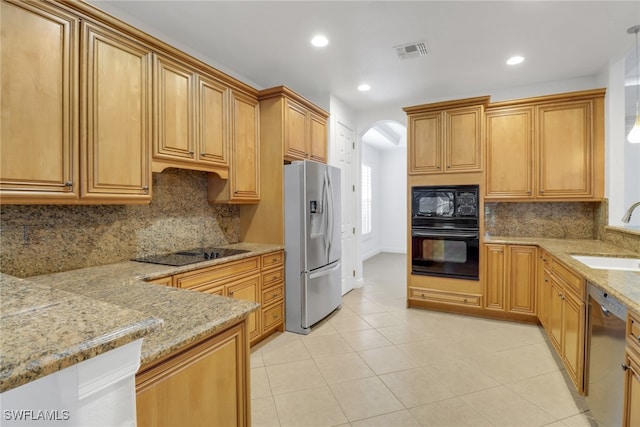 kitchen featuring black appliances, light stone countertops, visible vents, arched walkways, and a sink