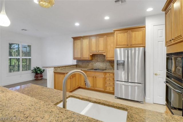 kitchen featuring tasteful backsplash, light stone countertops, a sink, and black appliances