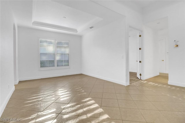 unfurnished room featuring light tile patterned floors, baseboards, and a raised ceiling