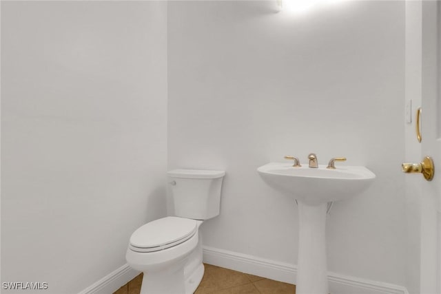 half bathroom featuring toilet, tile patterned floors, and baseboards