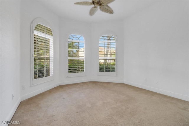 carpeted spare room with baseboards and a ceiling fan