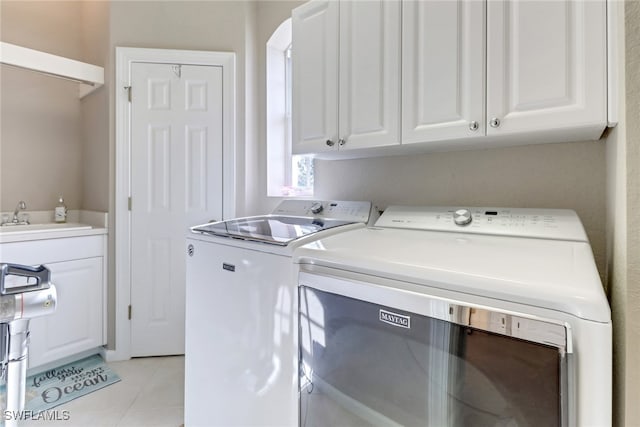 washroom featuring washer and dryer, cabinets, light tile patterned floors, and sink