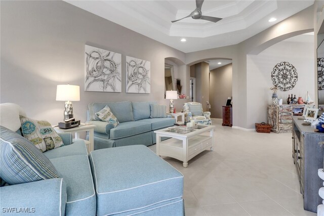 living room with ceiling fan, a raised ceiling, and ornamental molding