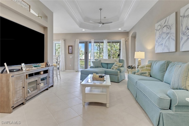 living room featuring ceiling fan, light tile patterned flooring, crown molding, and a tray ceiling