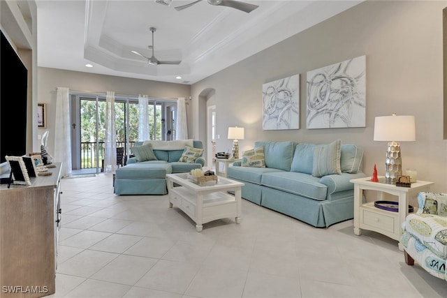 living room featuring ceiling fan, light tile patterned flooring, a raised ceiling, and crown molding