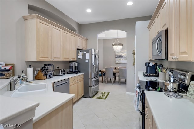 kitchen featuring sink, stainless steel appliances, light brown cabinetry, and an inviting chandelier