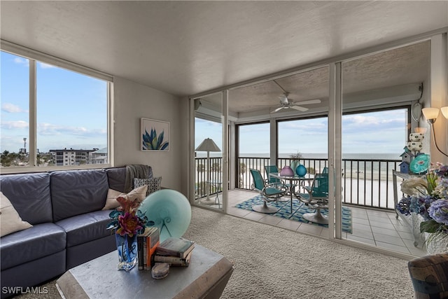 sunroom with ceiling fan and a water view