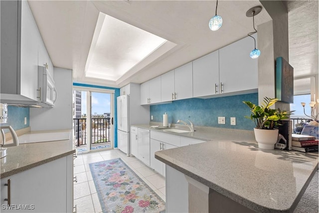 kitchen with sink, white appliances, white cabinets, decorative light fixtures, and kitchen peninsula