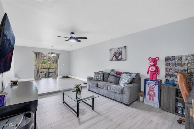 living room with ceiling fan with notable chandelier and light hardwood / wood-style floors