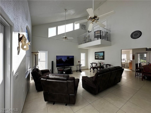 living room with ceiling fan, a wealth of natural light, light tile patterned floors, and high vaulted ceiling